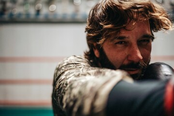Serious Hispanic sportsman boxing in gym