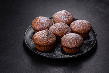 Beautiful delicious cupcakes with cocoa and raisins on a black concrete background