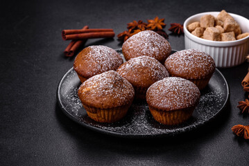 Beautiful delicious cupcakes with cocoa and raisins on a black concrete background