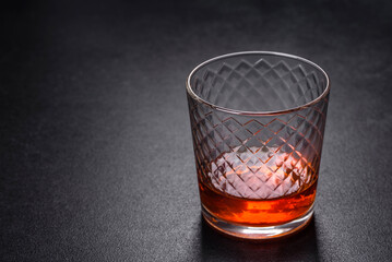 A glass of whiskey or cognac on a black concrete table. Relaxation time