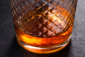 A glass of whiskey or cognac on a black concrete table. Relaxation time