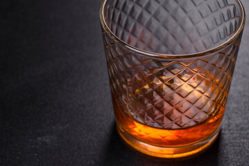 A glass of whiskey or cognac on a black concrete table. Relaxation time