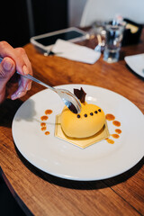 person hand holding a spoon eating a heart shaped cake decorated with yellow icing, catering in restaurant, delicious gourmet food, studio