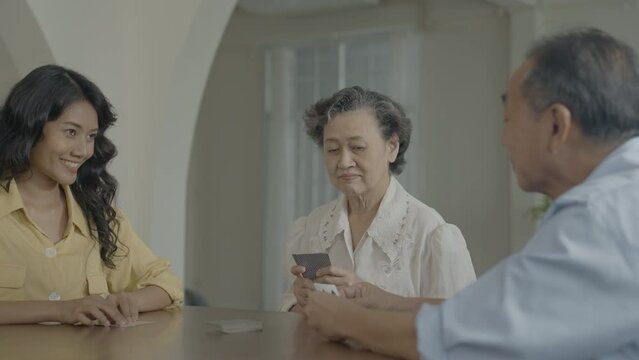 Holiday concept of 4k Resolution. Asian families take turns discarding cards on the table while playing games at home. Family gambling games.