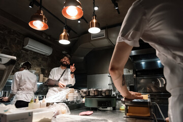 Cheerful chef pointing at male colleague