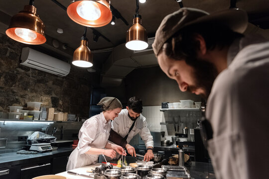 Man and woman cooking dish near coworker