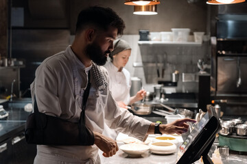 Male chef using computer in restaurant kitchen