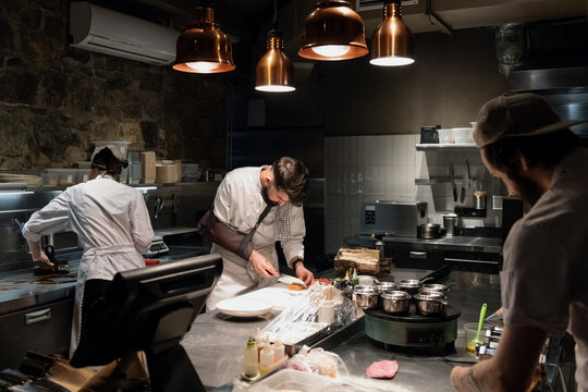 Cooks preparing various dishes in restaurant kitchen - Powered by Adobe