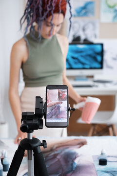 Woman creating fluid art in front of smartphone