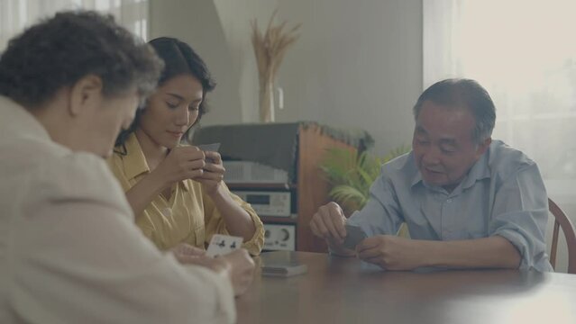 Holiday concept of 4k Resolution. Asian families take turns discarding cards on the table while playing games at home. Family gambling games.