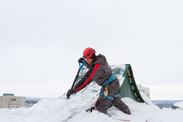 Fototapeta na wymiar Climber clears snow from roof