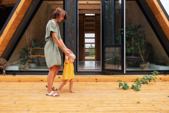 Mom teaching toddler to walk on porch