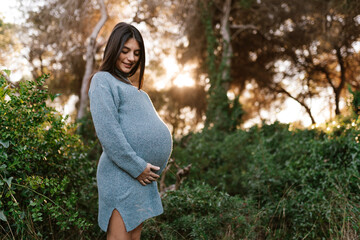 Smiling ethnic pregnant woman touching belly