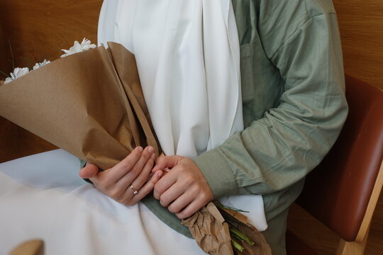 hand of young girl holding a bouquet of white daisies