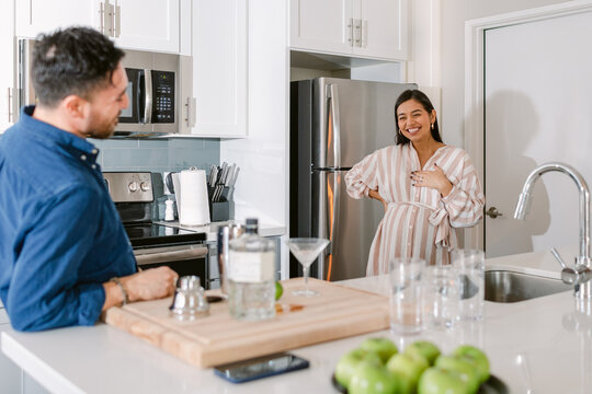 Expectant couple happily talking in kitchen