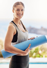 On my way to yoga class. Portrait of an attractive young woman carrying her yoga mat to class.