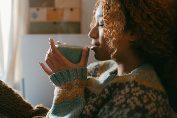 Person drinking hot beverage in cozy bedroom