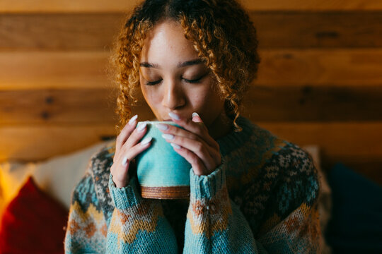 woman drinking tea in cozy bedroom in hygge season