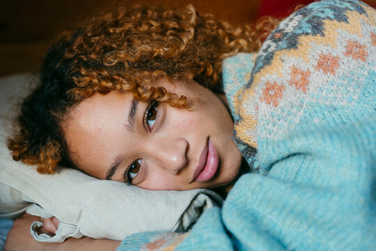 Girl lying on bed in winter clothes looking at camera
