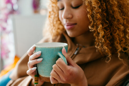 Young woman's hands holding a green cup in hygge season