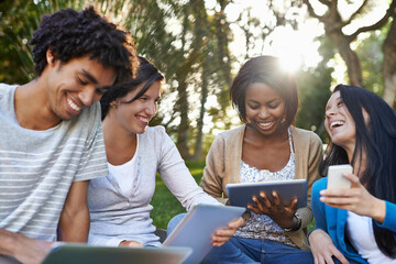 College diversity. Shot of a diverse group of college students sitting outside using digital tablet.