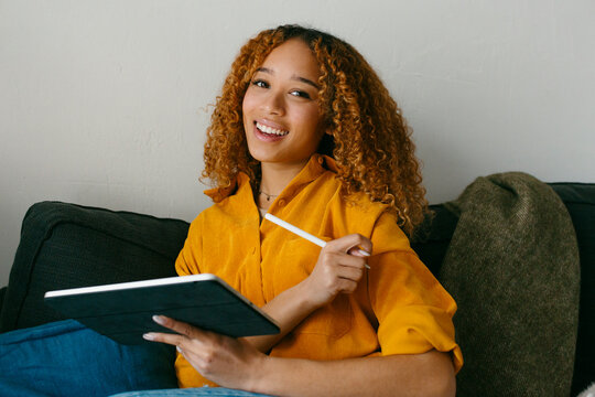 Teenager in yellow shirt with ipad looking at camera