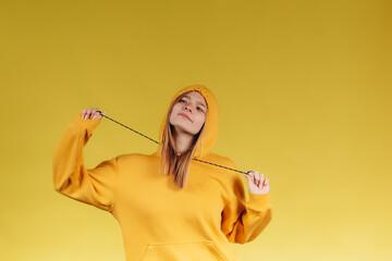 Portrait of a sad young teen girl wearing a casual yellow hoodie in one tone with the background