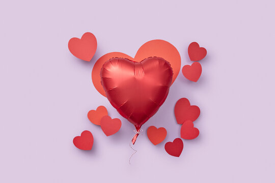 Red helium balloon surrounded with papercraft hearts