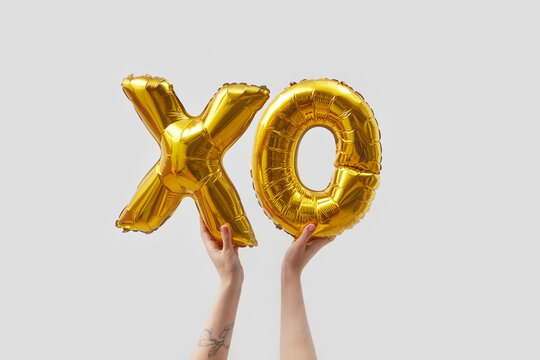 Woman holding balloons in shape of XO letters