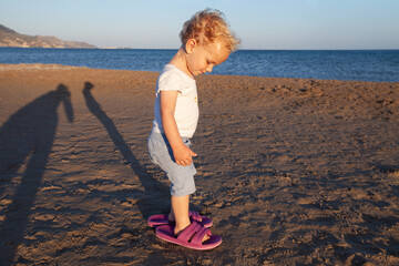 ugc, child wearing shoes too big on the beach