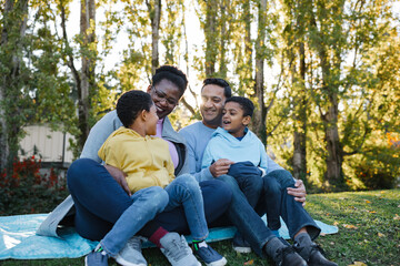 Family enjoys sitting on blanket together outside.