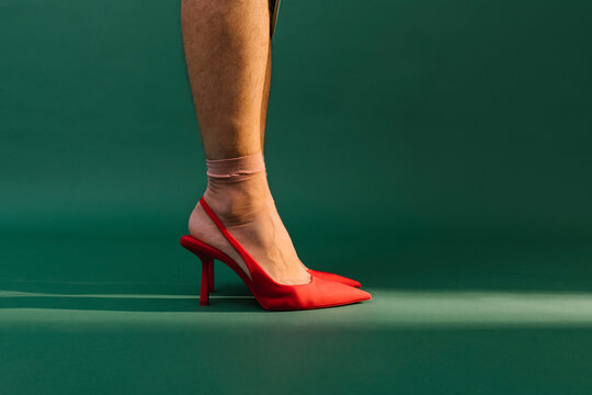 man with red high heels on green background