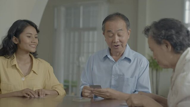 Holiday concept of 4k Resolution. Asian families take turns discarding cards on the table while playing games at home. Family gambling games.