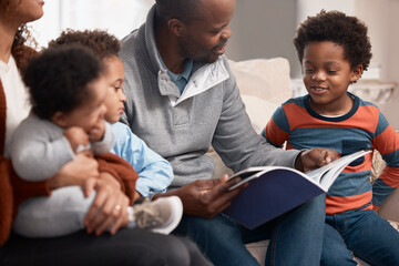 Its become a tradition in their family to read together. Shot of a father reading a book to his family at home.