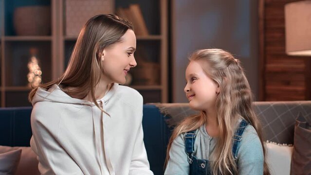 Happy mother and daughter smiling touching noses feeling love and tenderness at cozy evening home