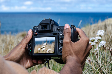 Anonymous female photographing flowers at seaside