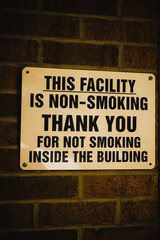 Naklejka premium A warning sign announcing that the facility is non-smoking inside, posted to the facility's brick wall in Chardon, Ohio