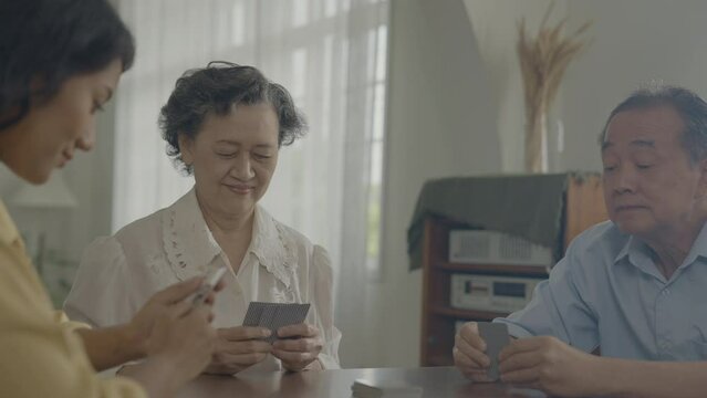 Holiday concept of 4k Resolution. Asian families take turns discarding cards on the table while playing games at home. Family gambling games.