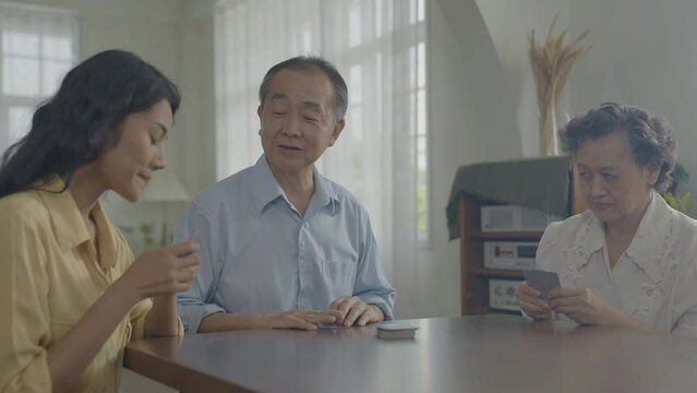 Holiday concept of 4k Resolution. Asian families take turns discarding cards on the table while playing games at home. Family gambling games.