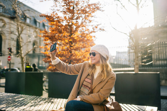Positive woman taking selfie in Paris