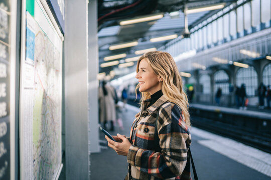 Happy lady with cellphone checking rout on platform
