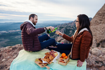 Young couple drink lemonade during mountain picnic
