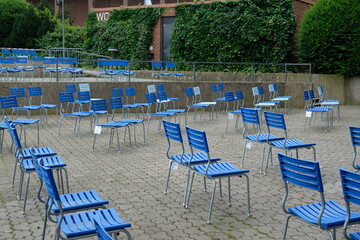 FU 2021-08-01 Rheinpark 51 Vor dem Gebüsch stehen leere blaue Stühle
