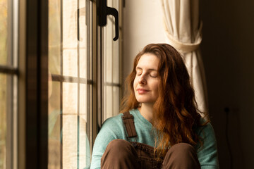Portrait of relaxed woman sitting by the window at home