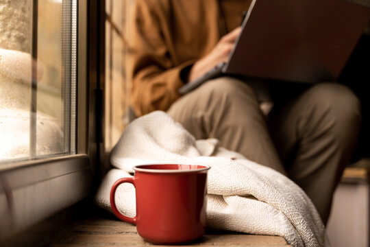 man sitting by the window using laptop