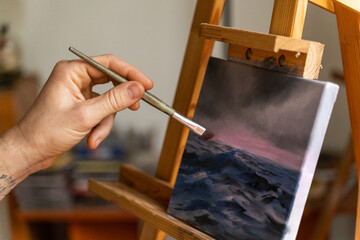 detail of man painting a canvas at home