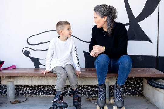 Mother and son chatting on bench before roller skating