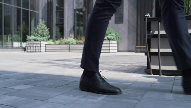 Confident manager walking downtown district on lunch break. Male legs closeup.