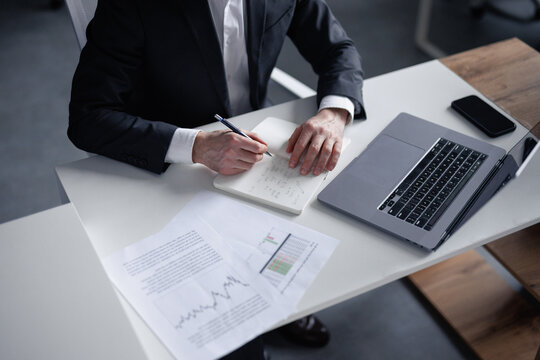 Faceless trader making trading calculations 