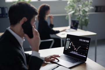 Man analyzing stock market and answering phone call